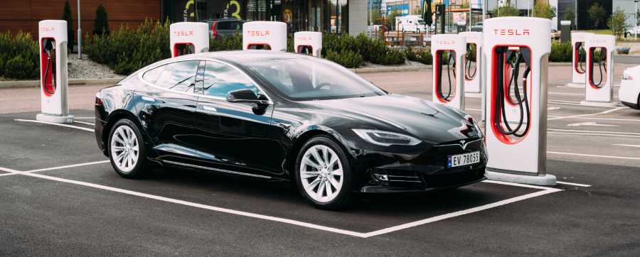 Black Tesla charging its car at one of the Tesla charging stations