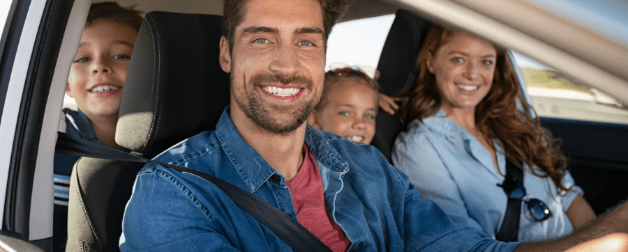 Grinning man with family sitting in a car