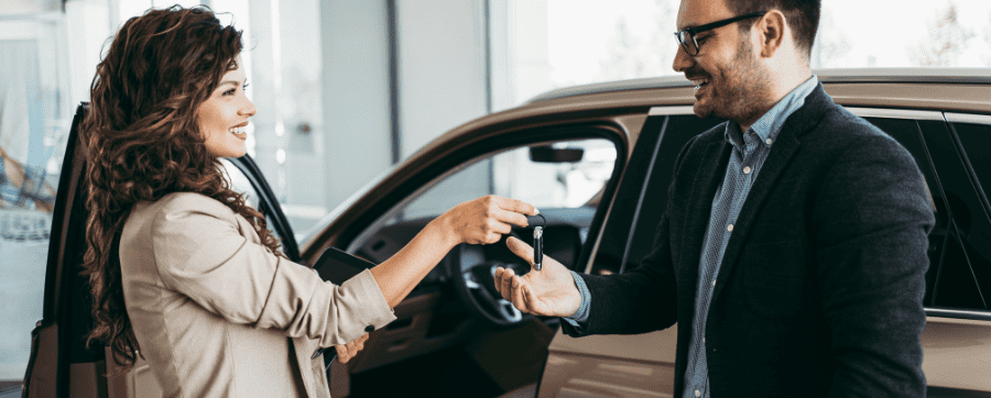 Woman and man smiling shaking hands securing a deal on a new car