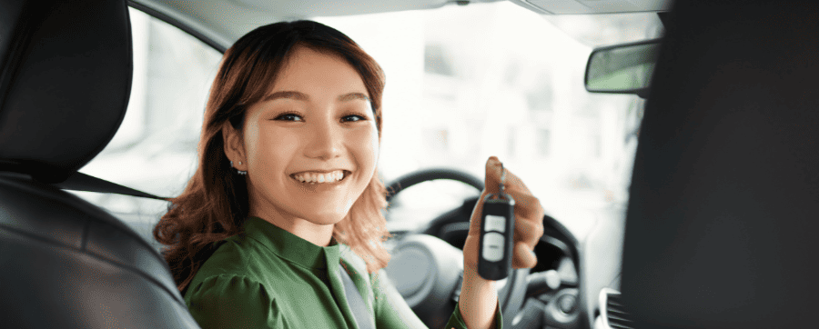 Woman smiling holding car keys inside a car
