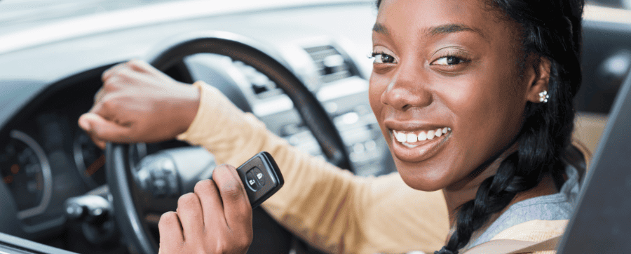 Women smiling holding a car key whilst sat in the drivers seat