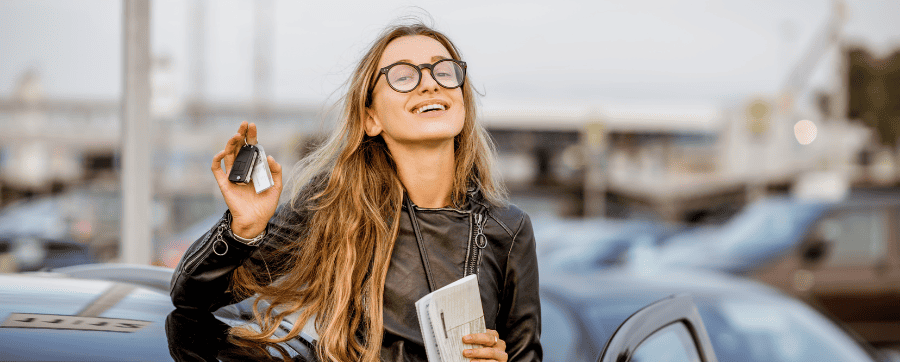 Smiling woman holding car keys in front of car - car subscription vs leasing