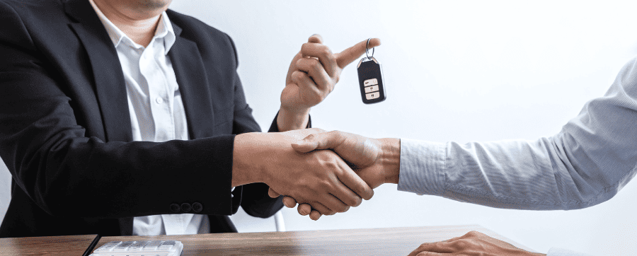 Person in suit shaking hands with another person whilst holding car keys - car subscription vs leasing