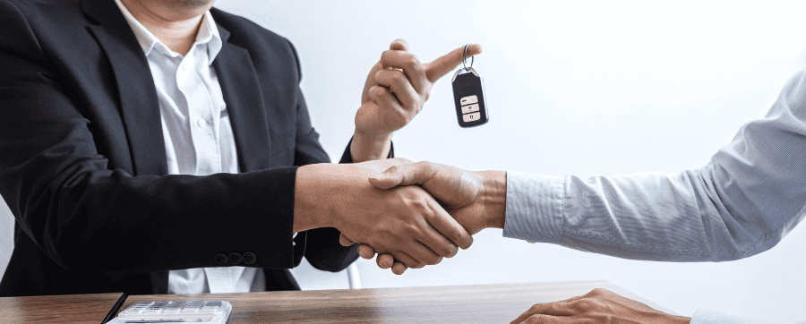 Two people shaking hands and handing over car keys when did car leasing become popular