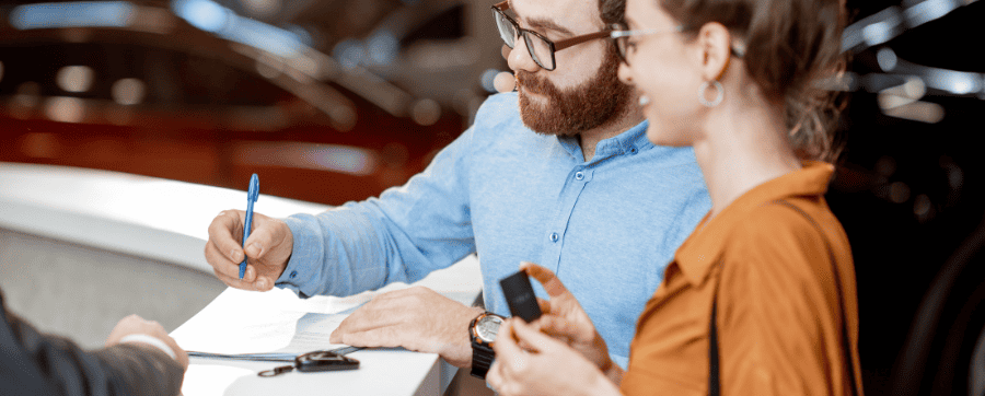 Couple smiling signing to buy a car - What happens at the end of a car lease?